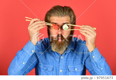 Man eat sushi chopsticks. Sushi rolls. Eastern culture. Bearded hipster eating rolls. Japanese food delivery. Pickled ginger served with sushi or sashimi. Japanese cuisine. Asian meal. Sushi roll 97951673