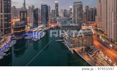 Aerial view to Dubai marina skyscrapers around canal with floating boats night to day timelapse Aerial view to Dubai marina skyscrapers around canal with floating boats night to day timelapse 97953397