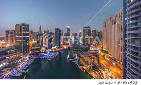 Aerial view to Dubai marina skyscrapers around canal with floating boats night to day timelapse 97953403