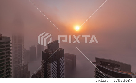 Rare early morning winter fog above the Dubai Marina skyline and skyscrapers lighted by sun aerial timelapse. Rare early morning winter fog above the Dubai Marina skyline and skyscrapers lighted by sun aerial timelapse. 97953637