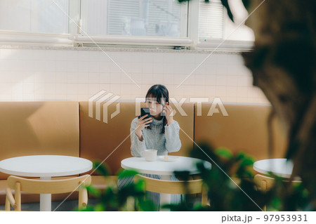 カフェで音楽を聴く若い女子大生の写真 カフェで音楽を聴く若い女子大生の写真 97953931