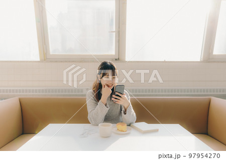 カフェでスマホをを触る若い女子大生の写真 97954270