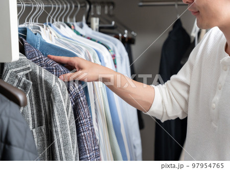 ウォークインクローゼットで服を選ぶ若い男性（ファッション・コーディネート） 97954765