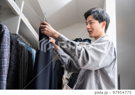ウォークインクローゼットで服を選ぶ若い男性（ファッション・コーディネート） 97954775
