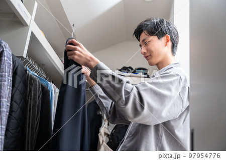 ウォークインクローゼットで服を選ぶ若い男性（ファッション・コーディネート） 97954776