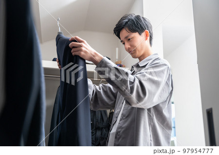 ウォークインクローゼットで服を選ぶ若い男性(ファッション・コーディネート) ウォークインクローゼットで服を選ぶ若い男性(ファッション・コーディネート) 97954777