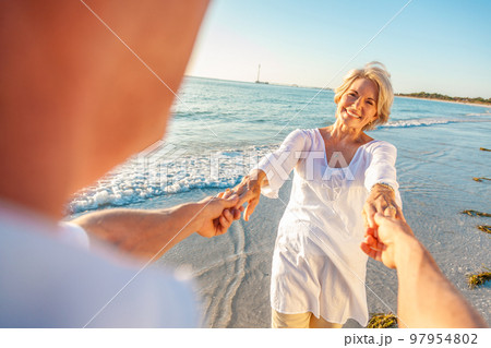 Happy Senior Old Retired Couple Dancing Holding Hands on a Beach 97954802