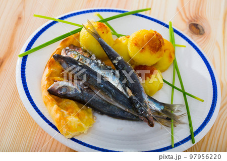 Dish of tasty fried anchovy with potato croquettes and cake served 97956220