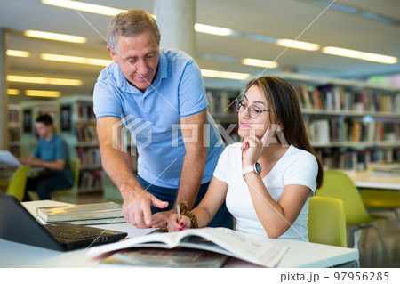 Elderly librarian helps young student find information she needs 97956285