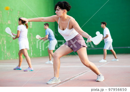 Woman serving ball during frontenis game outdoors Woman serving ball during frontenis game outdoors 97956650