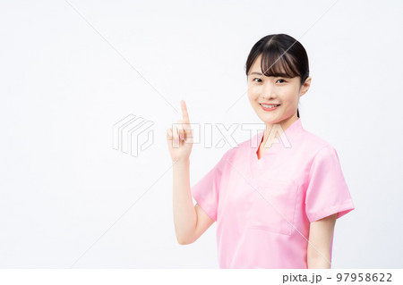 ピンクのスクラブを着た若い女性の看護師(指さしポーズ) ピンクのスクラブを着た若い女性の看護師(指さしポーズ) 97958622