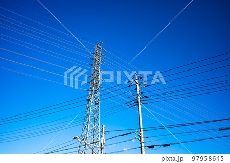 住宅街の電線と高圧送電線を支える送電鉄塔 見上げる快晴の空　高彩度コントラスト 97958645