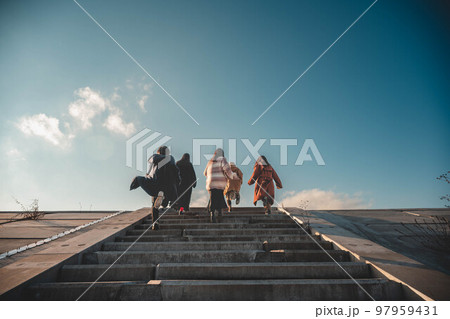友人5人で青空のもと楽しそうに階段を駆け上がる 97959431