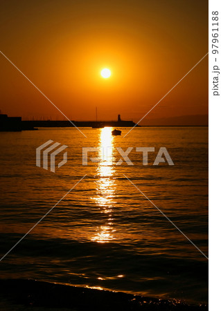 冬の夕暮れの逗子海岸、夕焼けに染まる空と日没前の太陽 97961188