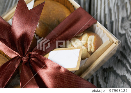 Homemade caramel. Brown caramel candies. Creamy sweets with peanuts. On pine boards. Packed in a box and tied with a ribbon. 97963125