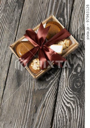 Homemade caramel. Brown caramel candies. Creamy sweets with peanuts. On pine boards. Packed in a box and tied with a ribbon. Homemade caramel. Brown caramel candies. Creamy sweets with peanuts. On pine boards. Packed in a box and tied with a ribbon. 97963126