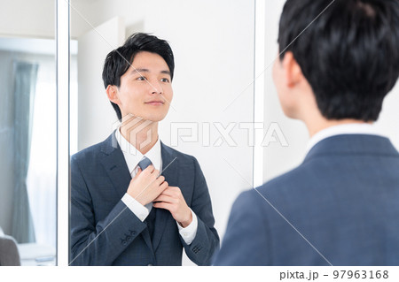 洗面所で鏡を見てネクタイを締める若いビジネスマン(朝・出勤準備) 洗面所で鏡を見てネクタイを締める若いビジネスマン(朝・出勤準備) 97963168