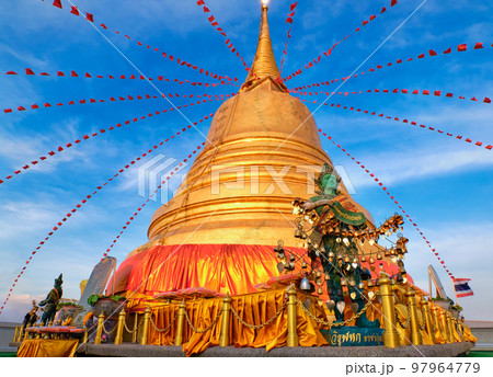 Thai angel by golden stupa in sunlight and blue sky in Buddhist temple. Thai angel by golden stupa in sunlight and blue sky in Buddhist temple. 97964779