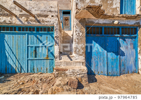 Faded and weathered white wall and stairs, blue painted door, Greece. Traditional architecture, details, authentic facade, sunny day, sunshine, shadow 97964785