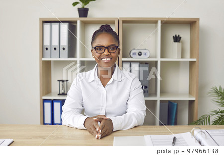 Portrait of happy young business woman sitting at office desk during online conference 97966138