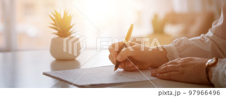 Woman's hands writing on sheet with a pen. 97966496