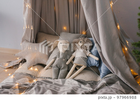 Toys on the bed surrounded by pillows on a baby bed surrounded by Christmas lights. Children's room interior 97966988