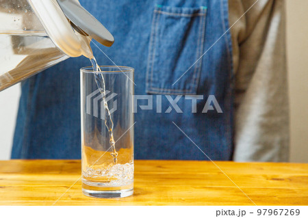 テーブルの上でコップに水を注ぐ様子 テーブルの上でコップに水を注ぐ様子 97967269