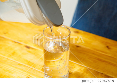 テーブルの上でコップに水が注がれる様子 97967319