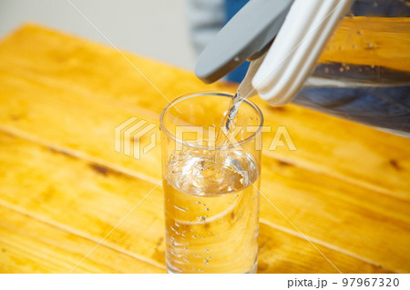 テーブルの上でコップに水が注がれる様子 97967320