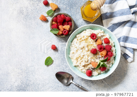 Healthy diet breakfast. Oatmeal porridge in ceramic bowl decorated with fresh berries raspberries and chia seeds served with honey. View from above. Copy space. 97967721