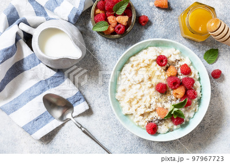 Oatmeal porridge in ceramic bowl decorated with fresh berries raspberries and chia seeds served with honey. Healthy diet breakfast. View from above. 97967723