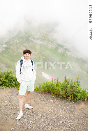 Looking at camera smiling european caucasian man with curly hair on nature mountain. Leisure activities in public park, deep fog. Mid adult lifestyle portrait. 97969513