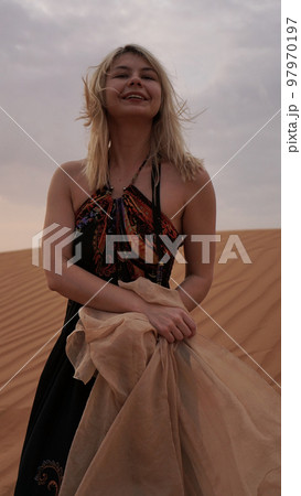 Woman in dress with a silk scarf, view of desert sand. Landscape vertical photo Woman in dress with a silk scarf, view of desert sand. Landscape vertical photo 97970197