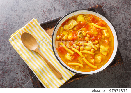Vegetable soup with meat, pasta and chickpeas close-up in a plate. horizontal top view Vegetable soup with meat, pasta and chickpeas close-up in a plate. horizontal top view 97971335