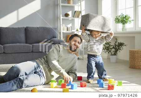 Happy father together with his little child playing with toy blocks in the living room Happy father together with his little child playing with toy blocks in the living room 97971426