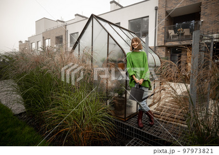Woman near greenhouse at backyard 97973821