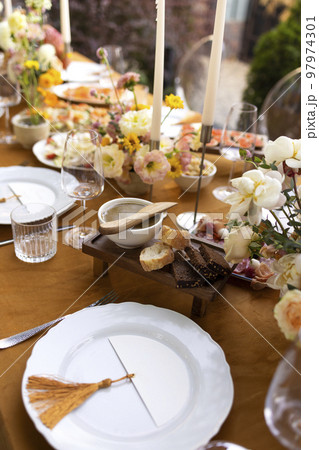 Wedding table for guests, decorated with candles, are served with cutlery and crockery and covered with yellow tablecloth Wedding table for guests, decorated with candles, are served with cutlery and crockery and covered with yellow tablecloth 97974301