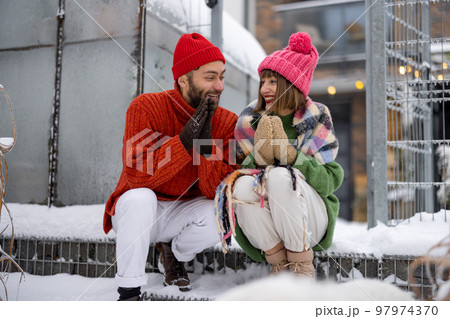 Young couple sit together on a porch of their house on winter 97974370