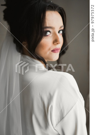 Luxury bride in white dress posing while preparing for the wedding ceremony Luxury bride in white dress posing while preparing for the wedding ceremony 97975572