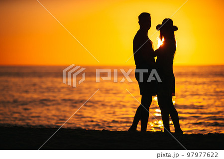 Young couple spending time together on the beach at sunset 97977622