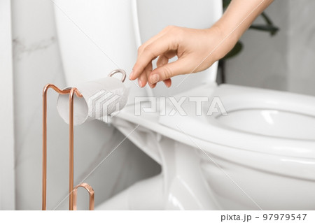 Woman reaching for empty toilet paper roll in bathroom, closeup 97979547