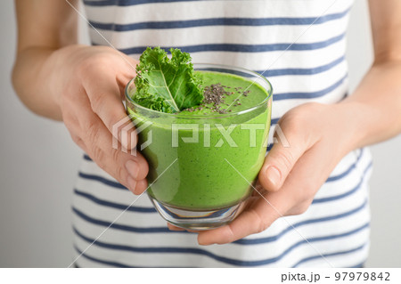 Woman holding tasty kale smoothie with chia seeds on light background, closeup Woman holding tasty kale smoothie with chia seeds on light background, closeup 97979842