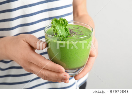 Woman holding tasty kale smoothie with chia seeds on light background, closeup Woman holding tasty kale smoothie with chia seeds on light background, closeup 97979843