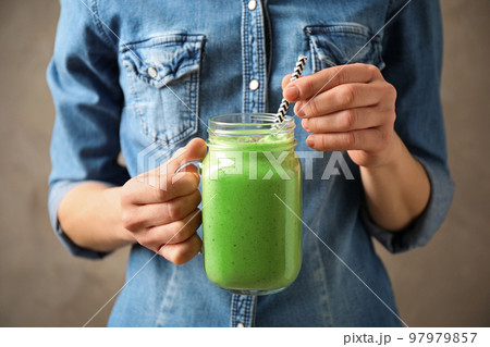 Woman holding tasty kale smoothie on brown background, closeup Woman holding tasty kale smoothie on brown background, closeup 97979857