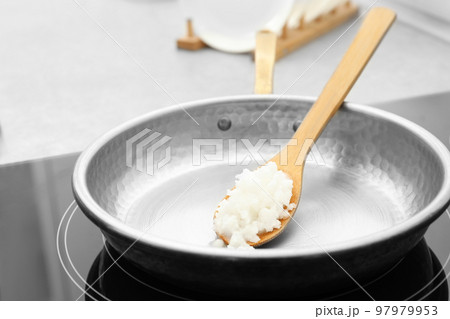 Frying pan with coconut oil on induction stove, closeup. Healthy cooking Frying pan with coconut oil on induction stove, closeup. Healthy cooking 97979953