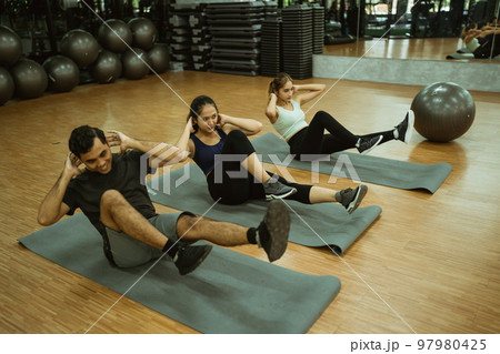group of sporty young people doing bicycle crunches on mats 97980425