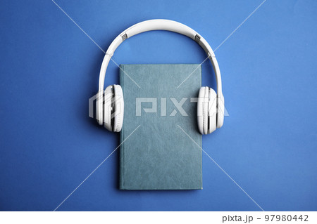 Book and modern headphones on blue background, top view Book and modern headphones on blue background, top view 97980442