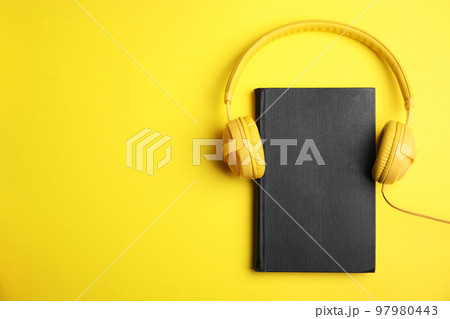 Book and modern headphones on yellow background, top view. Space for text Book and modern headphones on yellow background, top view. Space for text 97980443