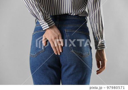 Woman suffering from hemorrhoid on light grey background, closeup 97980571