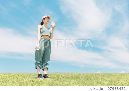 青空のもと公園でプロテイン・牛乳・豆乳を飲むアジア人女性 青空のもと公園でプロテイン・牛乳・豆乳を飲むアジア人女性 97983422
